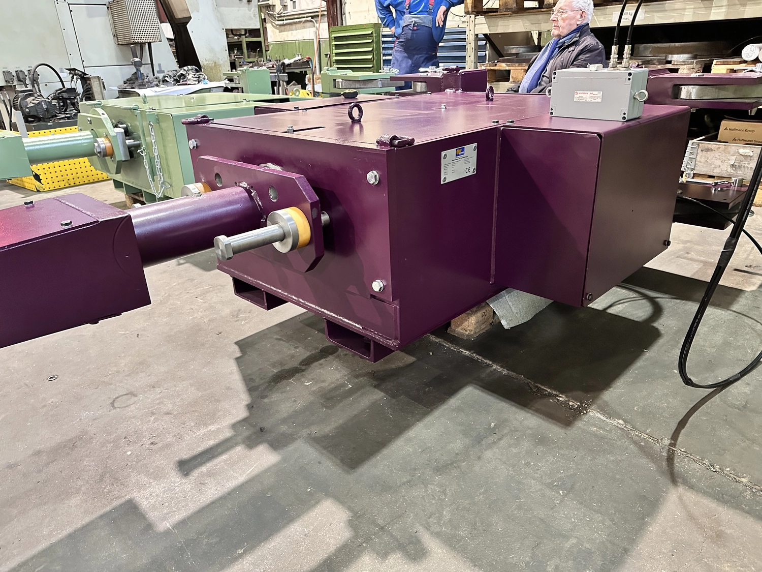 IGEMA Technology GmbH&Co.KG -  Maschinenbau & Verpackungstechnik Service -  Ein großes, violettes Industriemaschinenbauteil oder Getriebegehäuse auf dem Fabrikboden.