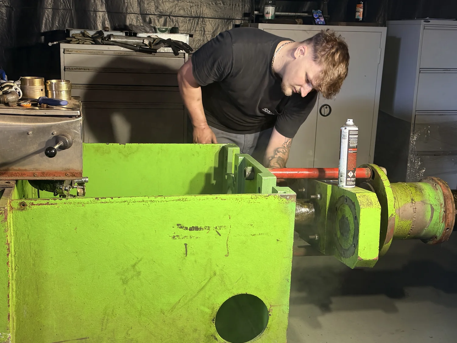 IGEMA Technology GmbH&Co.KG -  Maschinenbau & Verpackungstechnik Service - Ein Techniker arbeitet an einer großen grünen Baugruppe in einer Maschinenhalle.