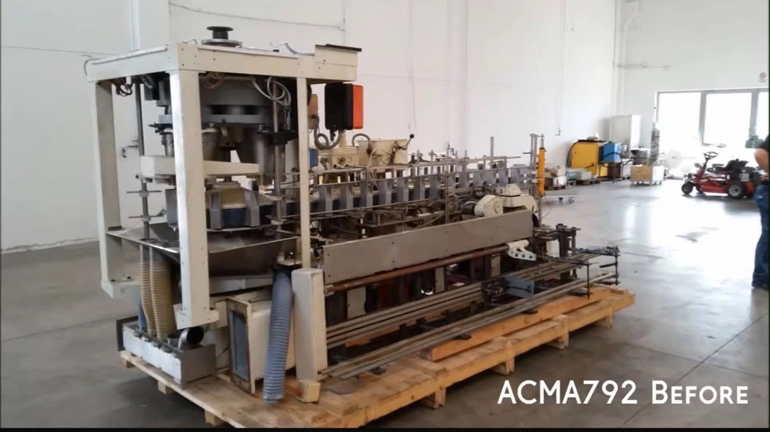 IGEMA Technology GmbH&Co.KG - Maschinenbau & Verpackungstechnik Service - ACMA792 Vorher: Ältere industrielle Abfüll- oder Verpackungsmaschine auf Holzpaletten, die auf eine Überholung wartet.