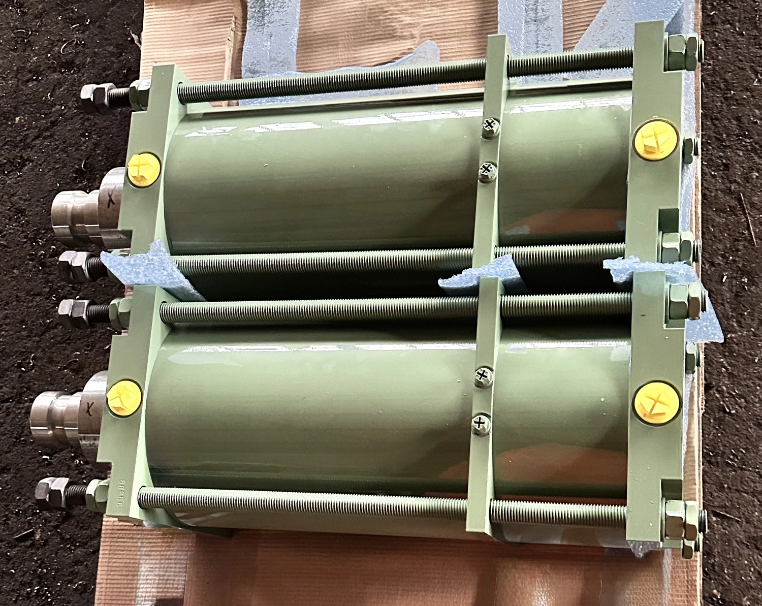 IGEMA Technology GmbH&Co.KG -  Maschinenbau & Verpackungstechnik Service - Zwei robuste grüne Hydraulikzylinder, die mit langen Stahlzugstangen verbunden sind.